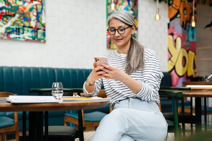 Frau im Büro mit Handy in der Hand